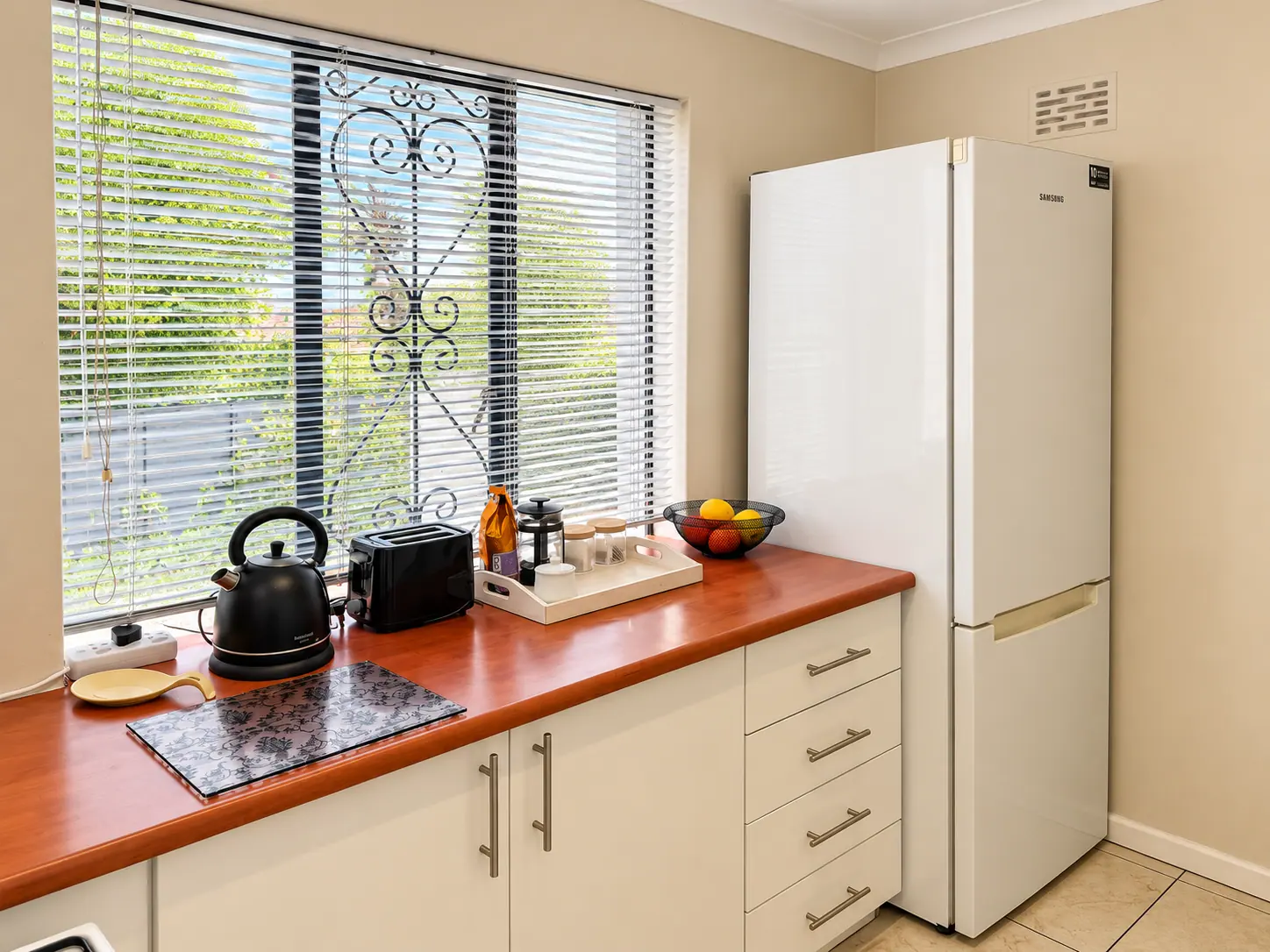 Bright kitchen counter with coffee tray and fridge